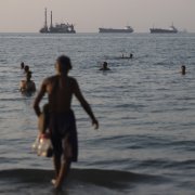 Embarcaciones de carga y comerciales ancladas en el Estrecho de Ormuz, mientras los residentes de Bandar Abbas se entretienen en el agua.