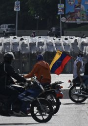 Manifestantes conducen sus motocicletas frente a miembros de la Guardia Nacional Bolivariana durante una protesta contra el gobierno de Nicolás Maduro en Caracas