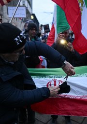 Un manifestante corta la bandera de la República Islámica de Irán