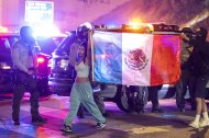 Manifestantes caminan junto a alguaciles con la bandera mexicana