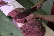 Un carnicero corta un trozo de carne-Imagen de archivo