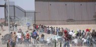 Migrantes en fila intentando cruzar la frontera entre Estados Unidos y México.