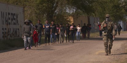 Un oficial de la Guardia Nacional de Texas guia a un grupo de inmigrantes hacia la Patrulla Fronteriza de Estados Unidos