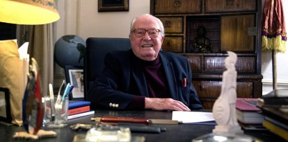 El político francés Jean-Marie Le Pen sentado detrás de un escritorio de su residencia privada.