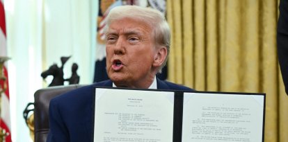 El presidente Donald Trump, habla mientras muestra la orden ejecutiva sobre aranceles recíprocos que firmó el 13 de febrero de 2025. (Foto de ANDREW CABALLERO-REYNOLDS / AFP)