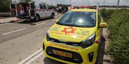 Los servicios de emergencia médica israelíes esperan en una carretera salpicada de barro a las afueras del aeropuerto israelí Ben Gurion tras el impacto de un misil cerca de las instalaciones el 4 de mayo de 2025.