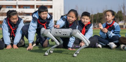 Los alumnos interactúan con un perro robot durante un descanso en clase en la escuela primaria Xinyi.