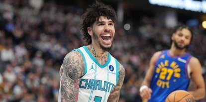 El base de los Charlotte Hornets, LaMelo Ball, reacciona tras clavar el balón para encestar mientras el base de los Denver Nuggets, Jamal Murray, observa en la segunda mitad de un partido de baloncesto de la NBA el domingo 18 de enero de 2026 en Denver.