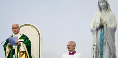 El papa León XIV (izquierda), flanqueado por el arzobispo italiano y maestro de las celebraciones litúrgicas pontificias Diego Ravelli, celebra, junto a la estatua de la Virgen María coronada, también conocida como «Nuestra Señora de Lourdes», la Santa Misa en la pradera del Santuario de Nuestra Señora de Lourdes, en el suroeste de Francia, el 27 de septiembre de 2026, en el tercer día de su visita a Francia.
