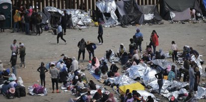 Migrantes atrapados entre las vallas primaria y secundaria en la frontera entre Tijuana y San Diego, visto desde Tijuana, México.