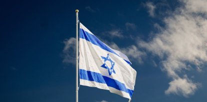 Bandera del estado de Israel flameando contra un cielo azulado con pocas nubes.