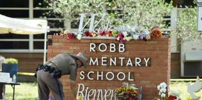 Un agente de policía de Uvalde deposita fotos en la escuela en la que se produjo la masacre.