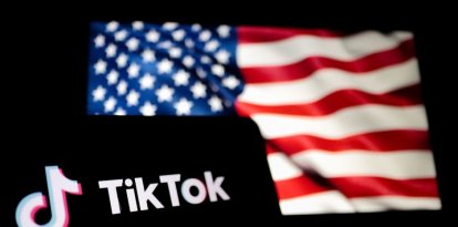 Un smartphone con el logo de TikTok delante de una bandera de los Estados Unidos.