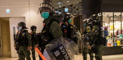 La policía antidisturbios establece un cordón en un centro comercial después de que prostíbulos se reunieran para conmemorar un año desde que un grupo de hombres vestidos de blanco atacaron a manifestantes pro-democracia que regresaban a casa después de protestas en la cercana estación de tren de Yuen Long, en Hong Kong el 21 de julio de 2020. / AFP / DALE DE LA REY