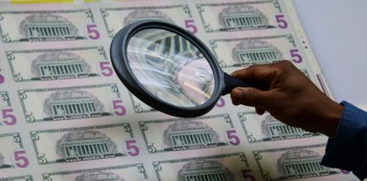 Un empleado examina una hoja de billetes de 5 dólares al salir de la máquina de impresión en la Oficina de Grabado e Impresión del Tesoro de EE.UU. en Washington.