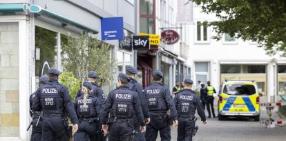 25 August 2024, North Rhine-Westphalia, Solingen: Police officers walk past the scene at midday. Three people were killed and several injured in an attack at the 650th anniversary celebrations of the city of Solingen on 23.08.2024. Photo: Thomas Banneyer/dpa