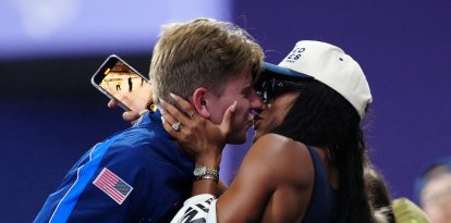 Gold medallist US' Hunter Woodhall (L) celebrates with his wife Olympic women's long jump champion Tara Davis-Woodhall after the victory ceremony for the Men's 400m T62 final event at the Stade de France in Saint-Denis, outside Paris on September 6, 2024. (Photo by Dimitar DILKOFF / AFP)