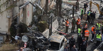 Varias personas observan el estado de varios vehículos en  Kiryat Bialik (Haifa) tras el ataque de Hizbulá.