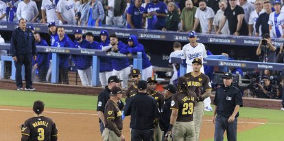 Los jugadores de los Padres de San Diego reciben instrucciones mientras que el Juego 2 de la NLDS del domingo 6 de octubre de 2024 se detiene debido a que los aficionados lanzan basura y pelotas de béisbol al campo en la 7ª entrada del partido entre los Dodgers de Los Ángeles y los Padres de San Diego en el Dodger Stadium de Los Ángeles, California. Jurickson Profar y Fernando Tatis hablan con los árbitros mientras les lanzan pelotas y basura.