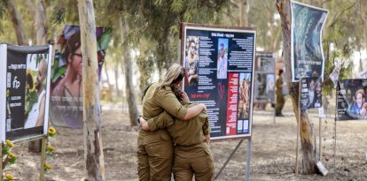 Guerra en Israel: Soldadas del ejército israelí se abrazan mientras visitan un monumento en memoria de las víctimas asesinadas o secuestradas en el festival de música Supernova