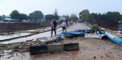 Miembros de una familia caminan por una calle cubierta de barro tras las inundaciones