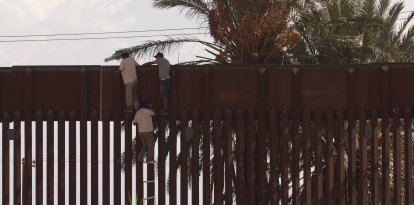 Crisis fronteriza: Migrantes utilizan una escalera de cuerda para saltar ilegalmente el muro fronterizo que separa Estados Unidos de México el 6 de octubre de 2022 en El Centro, California.