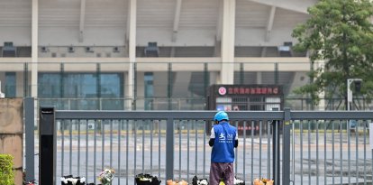 Un repartidor deposita pedidos online de ramos de flores en un monumento improvisado frente al Centro Deportivo de Zhuhai