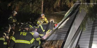 Bomberos asistiendo un trailer donde cayó un árbol durante una bomba ciclónica.