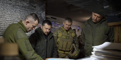 El presidente ucraniano Volodimir Zelenski es informado por un comandante durante su visita a un cuartel.