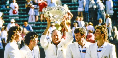 El entrenador Neale Fraser levanta el trofeo con los jugadores mirando