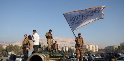 Terroristas islamistas una bandera blanca de la yihad sobre un tanque en Damasco tras derrocar al régimen de Asad