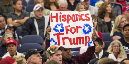 Un hombre sostiene un cartel en el que se lee "Hispanos por Trump"