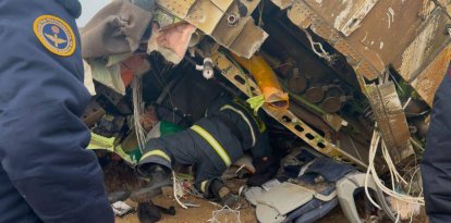 Unos bomberos revisan el lugar de colisión del avión de Azerbaijan Airlines, en el que quedan restos de la aeronave.