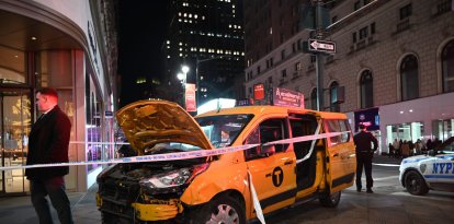 Un taxi accidentado, sni las partes delanteras del chasis, descansa en una zona acornada de una acera de Nueva York.