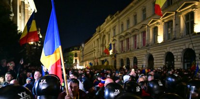 Un partidario del candidato presidencial Calin Georgescu sostiene la bandera rumana.