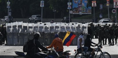 Manifestantes conducen sus motocicletas frente a miembros de la Guardia Nacional Bolivariana durante una protesta contra el gobierno de Nicolás Maduro en Caracas