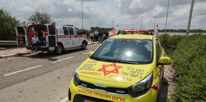 Los servicios de emergencia médica israelíes esperan en una carretera salpicada de barro a las afueras del aeropuerto israelí Ben Gurion tras el impacto de un misil cerca de las instalaciones el 4 de mayo de 2025.