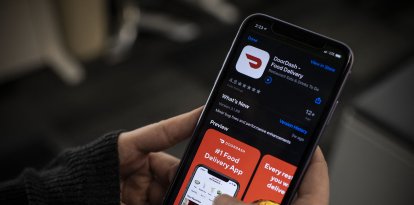 Una periodista de AFP comprueba la aplicación de entrega de comida a domicilio DoorDash en su smartphone el 27 de febrero de 2020 en Washington, DC. DoorDash inició el 27 de febrero de 2020 el proceso de salida a bolsa con una oferta de acciones en Estados Unidos que podría valorar el popular servicio de entrega de comida a domicilio en más de 10.000 millones de dólares.