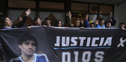 Fans del fallecido astro del fútbol Diego Maradona sostienen una pancarta que dice en español 