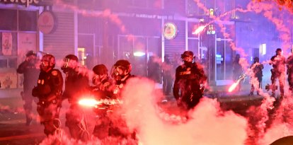 Fuegos artificiales explotan alrededor de agentes de policía con equipo antidisturbios durante una protesta en respuesta a las operaciones federales de inmigración en el barrio de Little Tokyo, en el centro de Los Ángeles, el 9 de junio de 2025. La administración del presidente Donald Trump dijo el 9 de junio que enviaba 700 marines estadounidenses y miles de efectivos más de la Guardia Nacional a Los Ángeles, lo que provocó una furiosa respuesta del gobernador de California por el "desquiciado" despliegue. Las protestas en Los Ángeles, hogar de una gran población latina, estallaron el 6 de junio, desencadenadas por redadas de inmigración que se saldaron con decenas de detenciones de lo que las autoridades dicen que son migrantes ilegales y miembros de bandas.