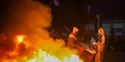Manifestantes enmascarados avivan una hoguera durante manifestaciones antiinmigración en Ballymena
