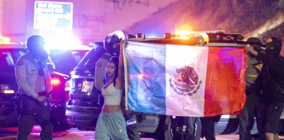 Manifestantes caminan junto a alguaciles con la bandera mexicana