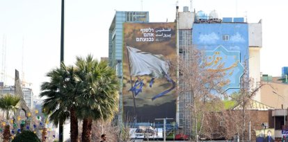 Iraníes pasan junto a un cartel antiisraelí en la Plaza Palestina de Teherán
