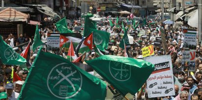 Banderas de los Hermanos Musulmanes, Jordania y otros partidos políticos ondean junto a otros carteles de protesta que denuncian la conferencia económica de Oriente Medio liderada por Estados Unidos en Baréin, durante una manifestación posterior a las oraciones del viernes contra el «Acuerdo del Siglo» del presidente estadounidense, Donald Trump, en la capital jordana, Ammán, el 21 de junio de 2019.