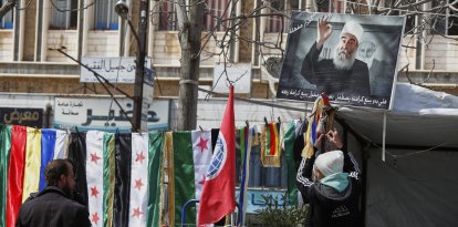 Un joven druso cuelga la imagen de Hikmat al-Hijri, líder espiritual de su comunidad en Siria