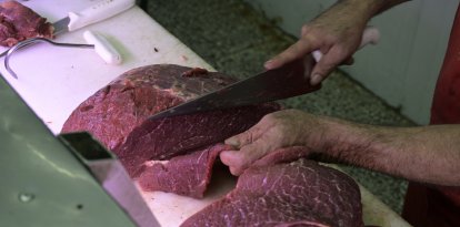 Un carnicero corta un trozo de carne-Imagen de archivo