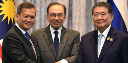 Malaysia's Prime Minister Anwar Ibrahim (C), Cambodia's Prime Minister Hun Manet (L) and Thailand's acting Prime Minister Phumtham Wechayachai (R) pose for photos as they shake hands following a press conference after talks on a possible ceasefire between Thailand and Cambodia in Putrajaya on July 28, 2025. Thailand and Cambodia began discussing a ceasefire in their festering border dispute on July 28, as the deadly skirmish dragged into a fifth day. (Photo by MOHD RASFAN / POOL / AFP)