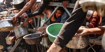 Palestinians crowd at a lentil soup distribution point in Gaza City in the northern Gaza Strip on July 27, 2025. (Photo by Omar AL-QATTAA / AFP)