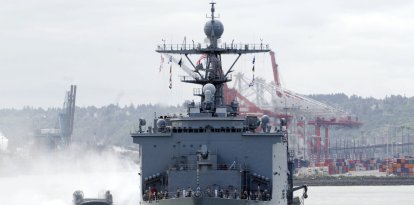 Una lancha de desembarco de colchón de aire (LCAC) sobrevuela la bahía de Elliott, detrás del buque de desembarco anfibio USS Rushmore (LSD 47), durante un desfile de barcos en conmemoración del centenario de la Gran Flota Blanca de Theodore Roosevelt. (Foto de la Marina de los EE. UU./Suboficial de segunda clase Jason Beckjord)