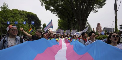 Una multitud carga una bandera transgénero